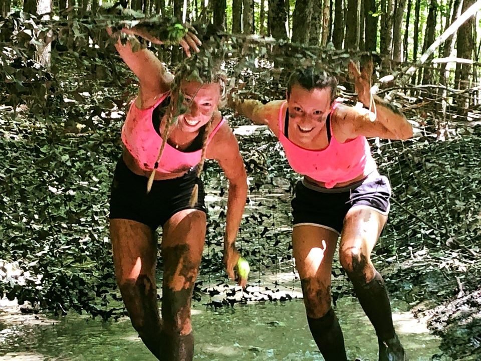 Amies couvertes de boue souriant dans la nature