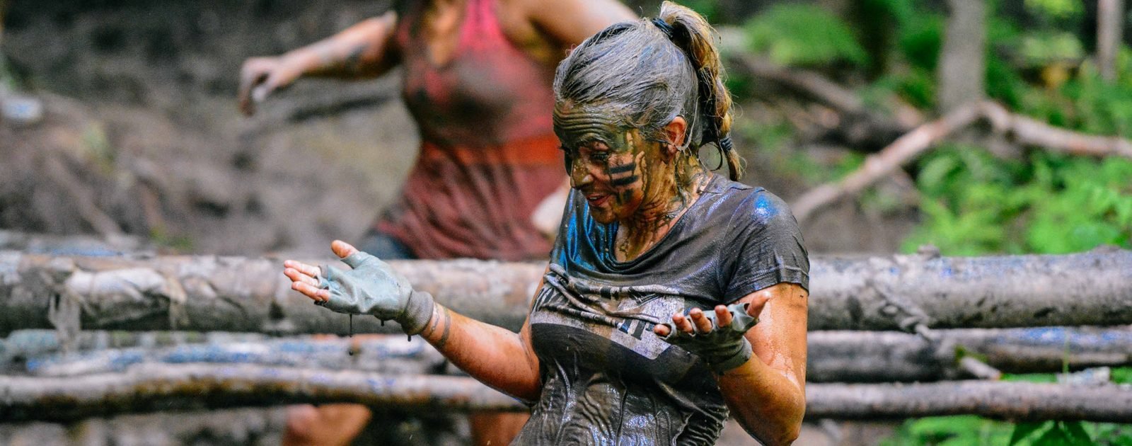 Participante couverte de boue souriant sur le parcours à obstacles