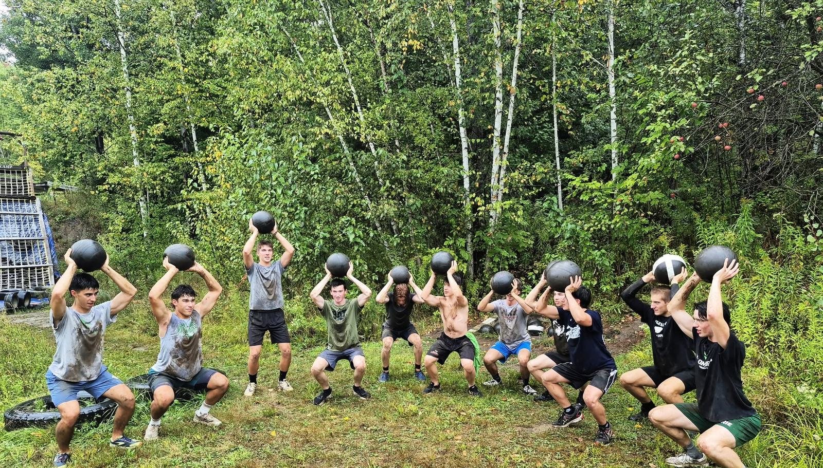 Équipe sportive s'entraînant ensemble avec ballons médicinaux au camp de base